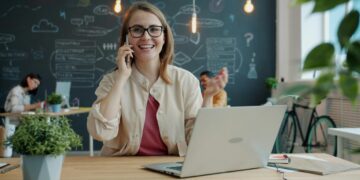 Smiling woman talking on phone in modern office.