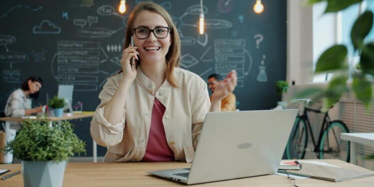 Smiling woman talking on phone in modern office.